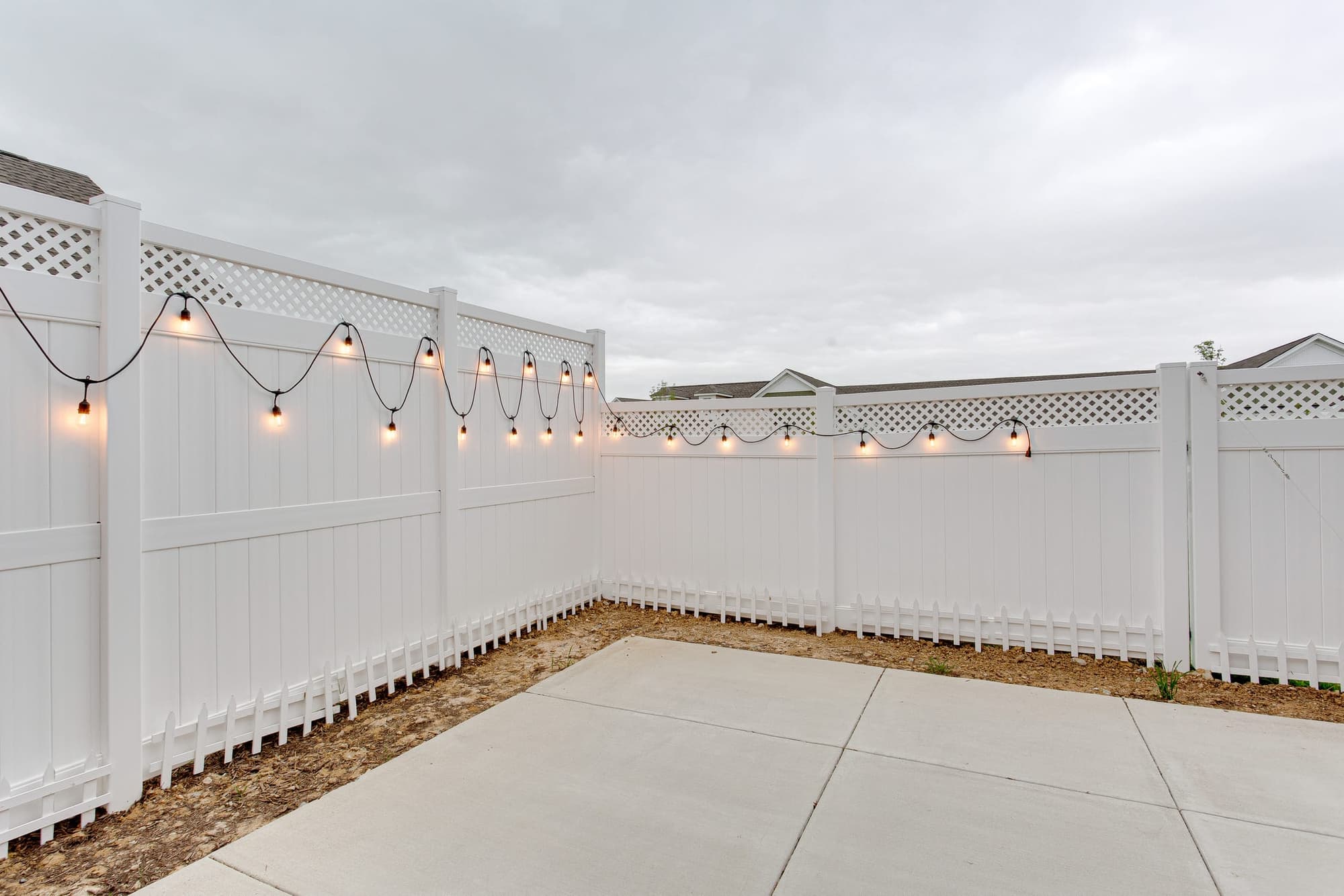 New concrete patio inside a white vinyl privacy fence