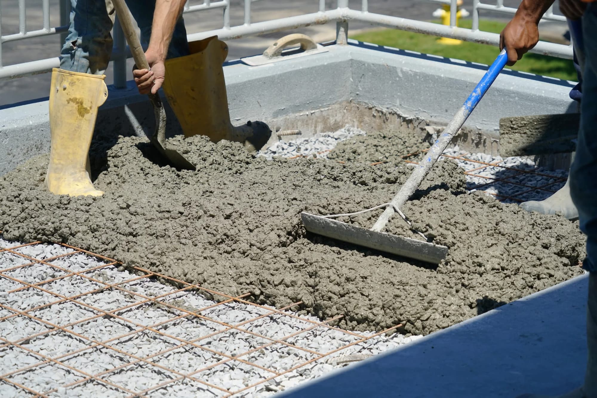 Fresh concrete spread over steel reinforcement inside slab forms