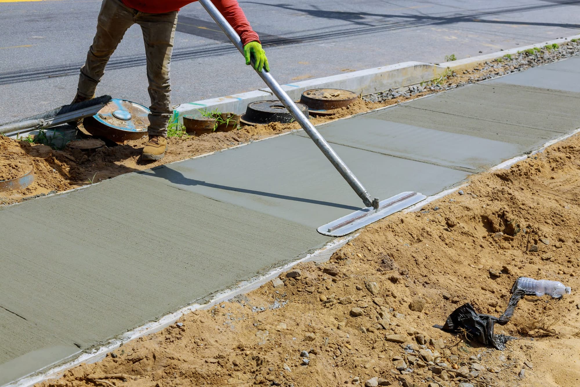 Finisher floating a new sidewalk beside the curb